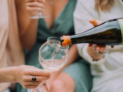 Casual gathering of women enjoying white wine outdoors, capturing a relaxed and joyful moment.